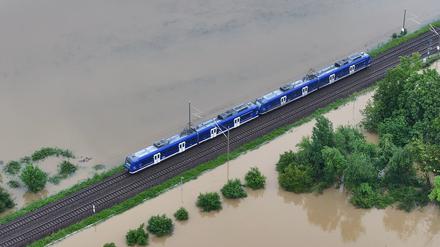 Ein Zug fährt über den höher gelegenen Bahndamm von Meckenbeuren, wo das Hochwasser des Flusses Schussen Teile des Ortes in Baden-Württemberg überschwemmt.