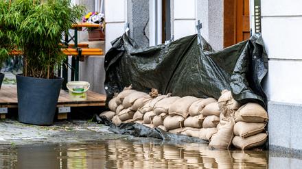 Sandsäcke liegen vor einem Haus. In Bayern herrscht nach heftigen Regenfällen vielerorts weiter Land unter.