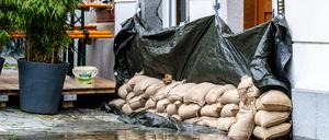 Sandsäcke liegen vor einem Haus. In Bayern herrscht nach heftigen Regenfällen vielerorts weiter Land unter.