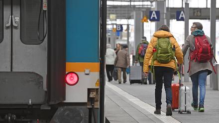 Fahrgaeste gehen mit ihrem Gepaeck auf einem Bahnsteig am Hauptbahnhof in Muenchen.