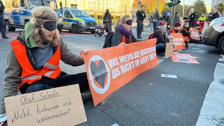 26.10.2022, Berlin: Demonstranten haben sich am Frankfurter Tor an die Straße geklebt. Sie demonstrieren gegen die nach ihrer Meinung zu geringen Maßnahmen der Politik gegen den Klimawandel. Foto: Julius-Christian Schreiner/dpa +++ dpa-Bildfunk +++