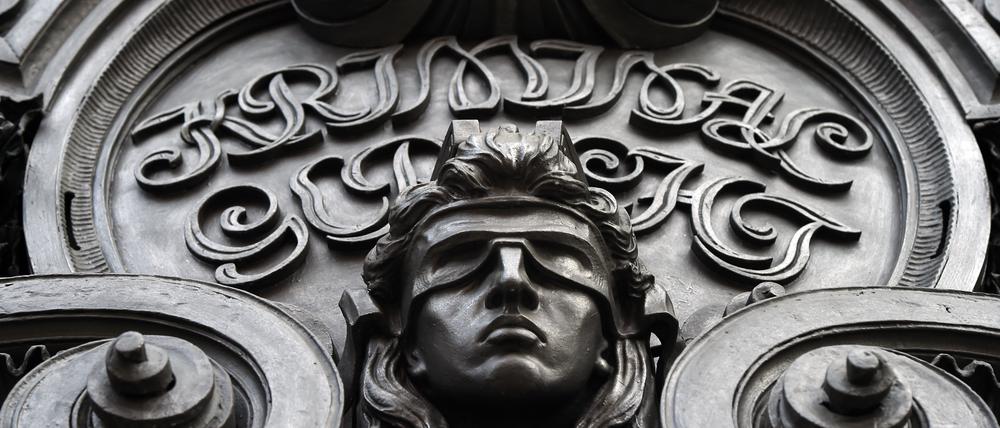 Eine Figur der blinden Justitia ist an der Fassade eines Kriminalgerichts zu sehen.