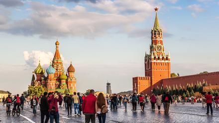 Menschen spazieren über den Roten Platz in Moskau. Links ist die Basilius-Kathedrale zu sehen, recht der Kreml.