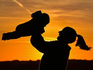 Eine Mutter ist mit ihrem acht Monate alten Baby im Sonnenuntergang auf einem Feldweg zu sehen. 