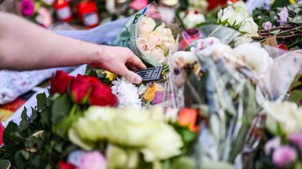 Bei einer Kundgebung unter dem Motto „Mannheim hält zusammen“, die anlässlich einer Messerattacke stattfindet bei der ein Polizist getötet wurde, legt ein Passant ein Polizeiwappen zu nieder gelegten Blumen.
