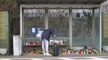Eine Reisende schaut sich die Blumen, Kerzen und verschiedene Bilder im Wartehäuschen am Bahnhof Brokstedt zum Gedenken an die Opfer der Messerattacke an.