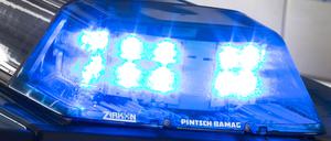 Ein Blaulicht leuchtet auf dem Dach eines Polizeiwagens. Im Hintergrund steht ein weiterer Streifenwagen. (Symbolbild)