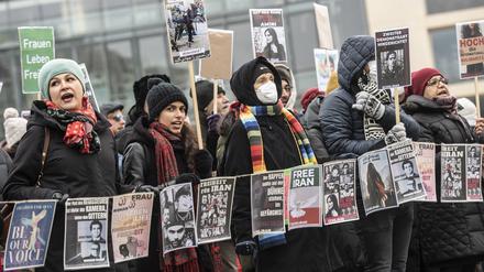 Teilnehmer an einer Protestaktion gegen das Iran-Regime stehen mit Plakaten auf dem Pariser Platz.