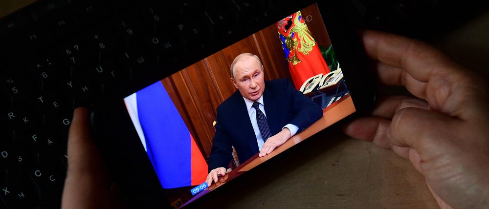 Ein Person schaut sich die Putin-Rede auf einem Mobiltelefon an.