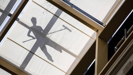 Schatten eines Arbeiters, der ein Glasdach reinigt.
