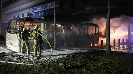 Feuerwehrleute löschen in der Silvesternacht an der Sonnenallee im Bezirk Neukölln einen brennenden Bus, der von Randalierern angezündet wurde.