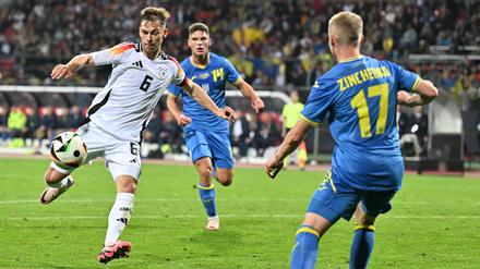 Vorbereitungsspiel der Nationalmannschaft gegen die Ukraine Joshua Kimmich, umgeben von zwei ukrainischen Spielern, schießt den Ball.