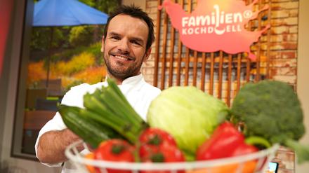 Steffen Henssler, fernseherfahrener Koch, steht in der Studiokulisse der Sendung „Familien-Kochduell“. 