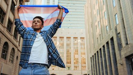 Ein trans Mann zeigt die trans Flagge in New York.