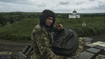 Ein ukrainischer Soldat zeigt ein Siegeszeichen auf einem Panzer an der Frontlinie. 
