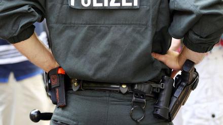Ein Polizist trägt Handschellen, Pistole, Schlagstock und eine Schutzweste.