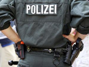 Ein Polizist trägt Handschellen, Pistole, Schlagstock und eine Schutzweste.