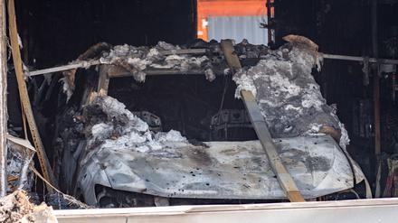 24.06.2023, Mecklenburg-Vorpommern, Jarmen: Ein ausgebranntes Auto steht in einer Garage an der Brandruine eines Einfamilienhaus in Jarmen.