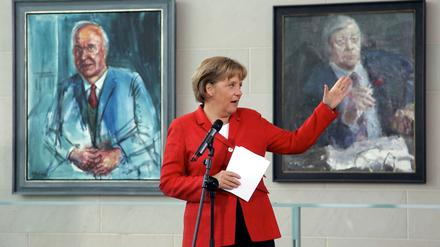 Bundeskanzlerin Angela Merkel (CDU) im Bundeskanzleramt in Berlin zwischen den Gemälden ihrer Amtsvorgänger Helmut Kohl (CDU, l) und Helmut Schmidt (SPD).