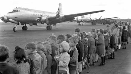 Kinder stehen auf dem Flughafen Berlin-Tempelhof und sehen der Landung eines US-amerikanischen Transportflugzeuges zu.