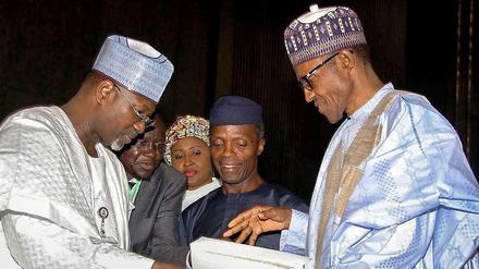 Der künftige Präsident Muhammadu Buhari (rechts) nimmt die Wahlergebnisse vom Chef der unabhängigen Wahlkommission Attahiru Jega (links) entgegen. In der Mitte steht der künftige Vizepräsident Yemi Osinbajo und im Hintergrund Buharis Ehefrau Aischa. 