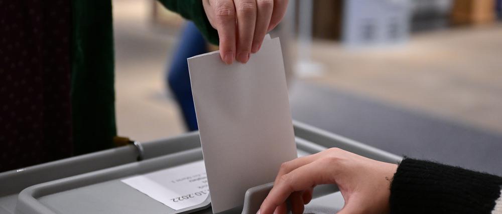 Ein Wähler steckt seinen Wahlzettel in eine Urne. 