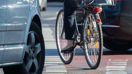 Eine Berliner Fahrradfahrerin radelt auf einem Radweg, während Autos rechts abbiegen. 