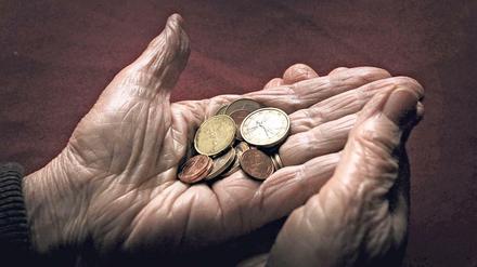 Eine 83-jährige Frau hält verschiedene Euromünzen. 