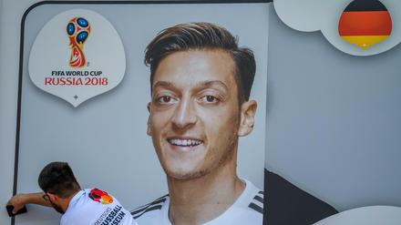 Helfer kleben ein Bild von Mittelfeldspieler Mesut Özil während der DFB-Pressekonferenz an die Außenwand des Fußballmuseums.