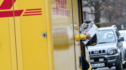 Ein DHL-Paketzusteller verlässt mit mehreren Sendungen sein Fahrzeug im Paulusviertel in Halle.