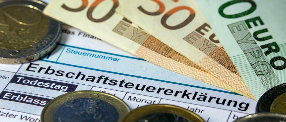 Formulare für die Erbschaftssteuererklärung des Finanzamtes zwischen Euro-Banknoten und Münzen