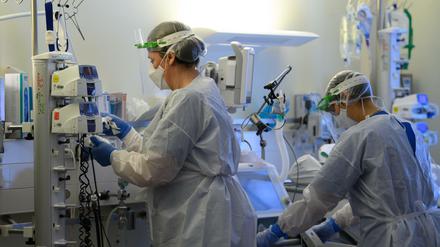  Intensivpflegerinnen sind auf der Covid-19-Intensivstation einer Klinik mit der Versorgung von Patienten beschäftigt.