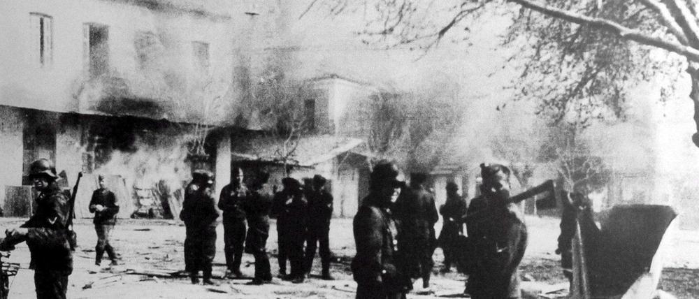Distomo 1944. Das Foto eines deutschen Teilnehmers zeigt seine Kameraden vor den brennenden Häusern nach dem Massaker an 218 Menschen.