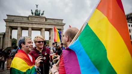 Männer mit Regenbogenflaggen feiern vor dem Brandenburger Tor in Berlin.