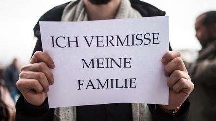 Ein Mitglied des Flüchtlingsrats Berlin hält ein Schild in den Händen.