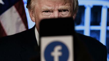 In dieser Illustration zeigt ein Telefonbildschirm ein Facebook-Logo mit dem offiziellen Porträt des ehemaligen US-Präsidenten Donald Trump im Hintergrund.