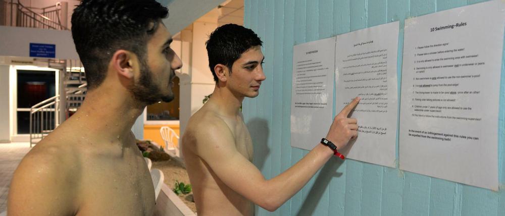 Es ist nie zu spät. Zwei nasse Flüchtlinge beim Studium der Baderegeln. 