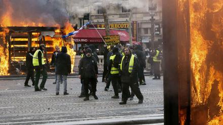 Krawall in Paris: Demonstranten der "Gelbwesten" stehen inmitten von brennenden Objekten und Rauchschwaden.