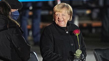 Angela Merkel nach ihrer Verabschiedung mit einer Rose in der Hand neben ihrem Mann, Joachim Sauer.