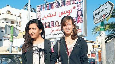 Demokratische Vorfreude. Zwei Studentinnen in Tunis, wo die Parteien vor der Wahl am Sonntag eifrig plakatierten. Insgesamt 90 Listen bewerben sich um Sitze in der verfassunggebenden Versammlung des Landes. 