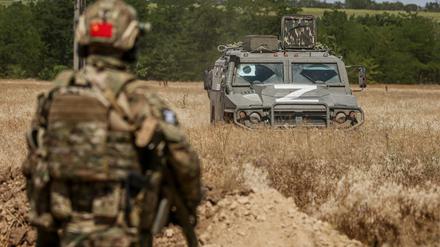 Ein russischer Soldat steht in der Ukraine vor einem Armeefahrzeug.