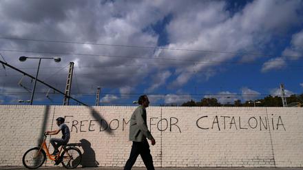 Menschen passieren in Barcelona eine Mauer mit dem Schriftzug "Freiheit für Katalonien". 