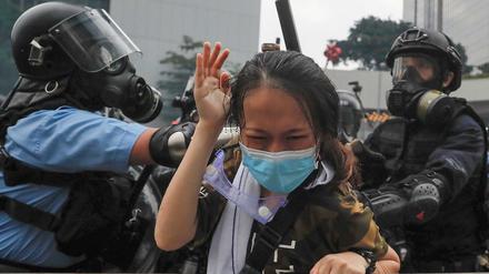 Hongkonger Polizisten drücken eine Demonstrantin gegen eine Absperrung. 