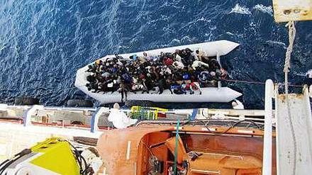 Ein Flüchtlingsboot neben dem Frachtschiff "OOC Cougar". Die Schiffe der Reederei Opielok Offshore Carriers haben seit Dezember vergangenen Jahres mehr als 1500 Menschen aus dem Mittelmeer gerettet. 