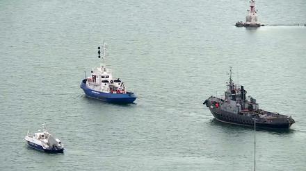 Ein beschlagnahmtes ukrainisches Schiff (r) wird von einem russischen Küstenwachboot aus dem Hafen von Kertsch geschleppt. 