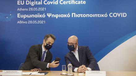 Der griechische Premierminister Mitsotakis (links) und EU-Ratschef Michel begutachten das digitale Impfzertifikat.