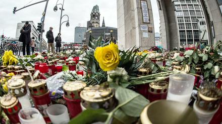 Passanten stehen am 26.12.2016 in Berlin vor einem Blumen- und Kerzenmeer am Breitscheidplatz, dem Ort des Anschlags. 