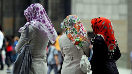 Türkischstämmige Frauen mit Kopftüchern stehen in der Kölner Fußgängerzone.