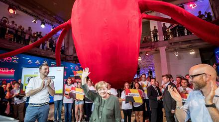 Bundeskanzlerin und CDU-Bundesvorsitzende Angela Merkel steht im "fedidwgugl"-Haus unter einem Herz, das wie ein Oktopus aussieht.