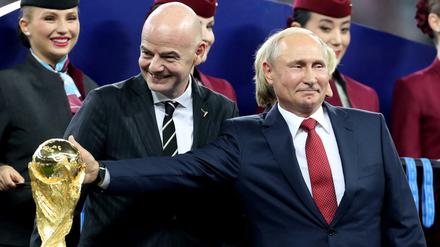 Wladimir Putin (vorne rechts), Präsident von Russland berührt nach dem Spiel neben Gianni Infantino, FIFA-Präsident den WM-Pokal.